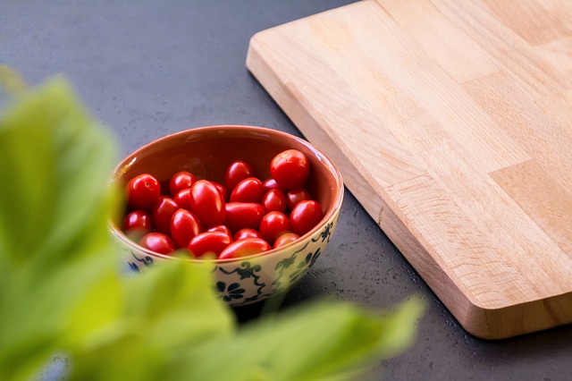 A bowl of fruit sitting on top of a wooden cutting board